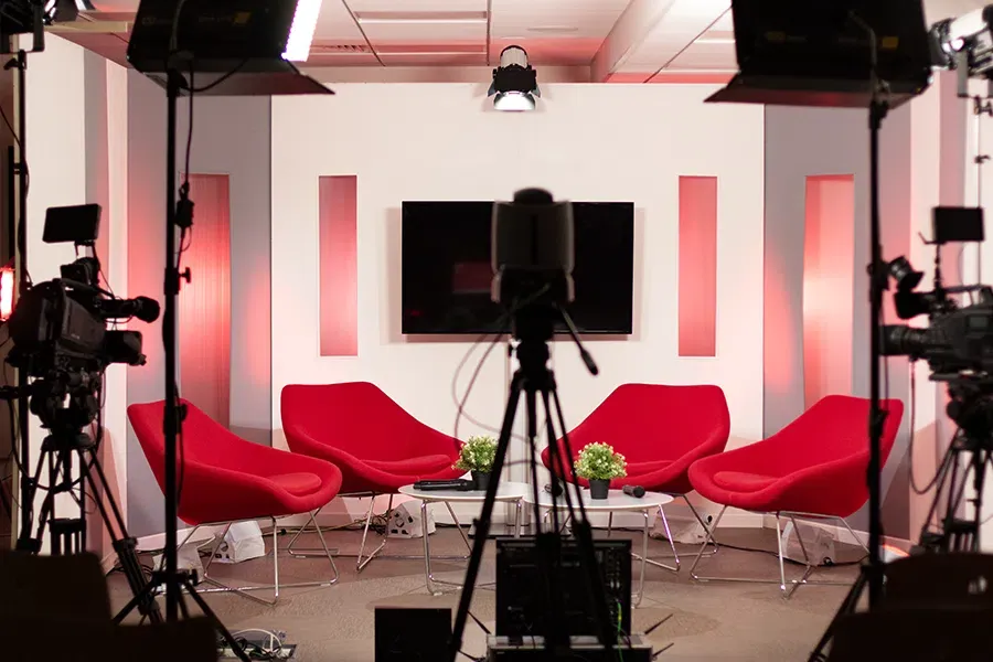 Studio de tournage de webinaire à quatre fauteuils rouges, écran central et plan lumière